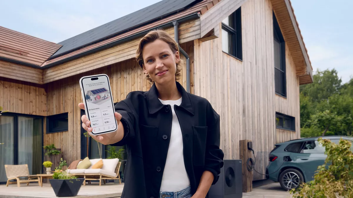 Frau mit Smartphone vor dem Haus